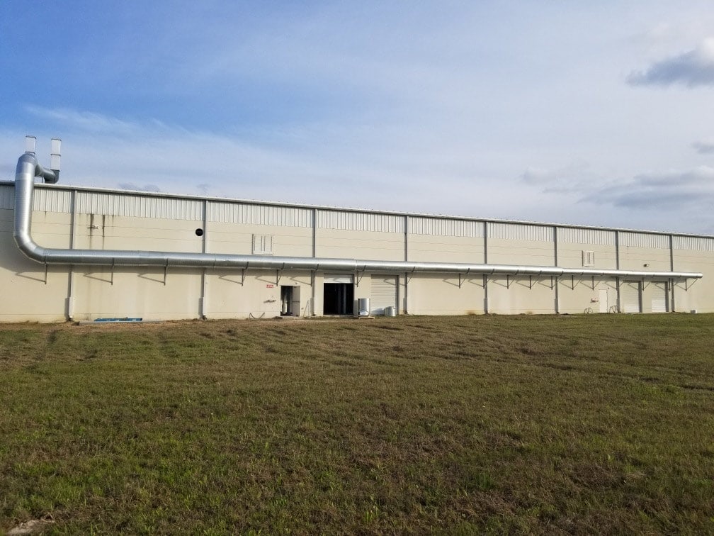 industrial exhaust ductwork system installed along exterior of manufacturing building