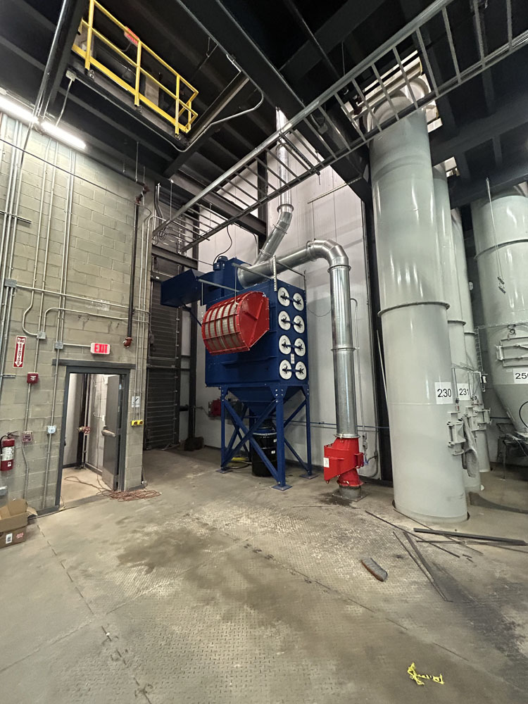 Indoor combustible dust collection system with explosion venting at a manufacturing facility