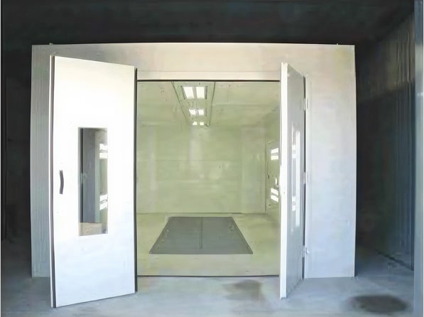 Interior view of industrial spray paint booth showing downdraft floor grate and overhead lighting system