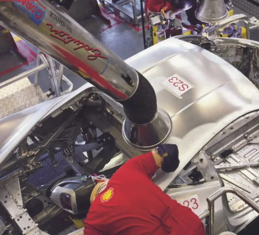 Welder using flexible fume extraction arm positioned at welding joint during aerospace manufacturing